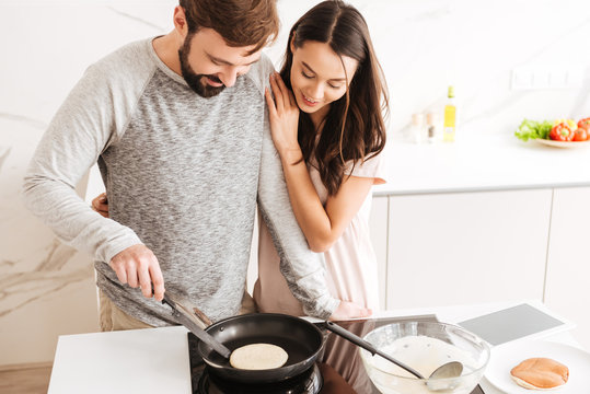Lovely young couple cooking pancakes together