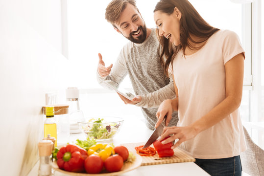 Portrait of an excited young couple cooking salad together