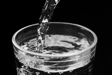 in a glass glass water pours, on a black background
