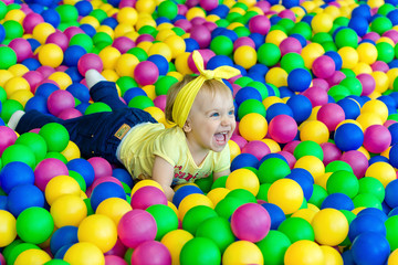 Fototapeta na wymiar Little girl laughing lying in balls