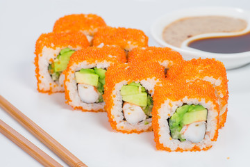 Appetizing California sushi rolls with rice, shrimps, avocado, cucumber and tobiko on light background