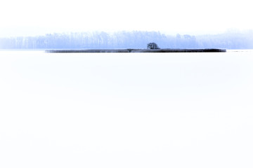 Winter landscape with frozen lake surface and woods in Masuria lakes district in Poland - Lasmiady lake near town of Elk