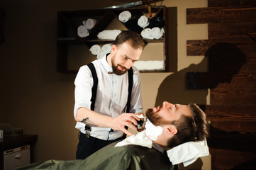 Master cuts hair and beard of men in the barbershop