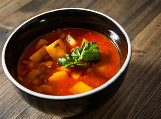Bean and vegetables soup in ceramic bowl on wooden table