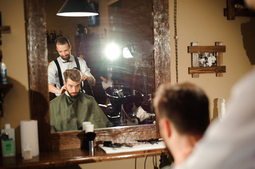 Master cuts hair and beard of men in the barbershop