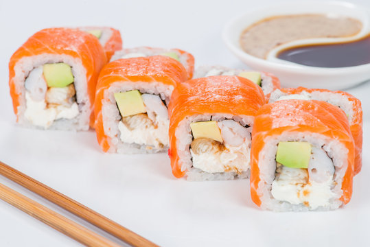 Tasty fresh sushi rolls with rice, cream cheese, shrimps, avocado, salmon and tobiko on light background