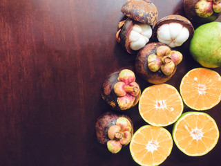 overhead view skin and texture of asia and summer fruit (mangosteen with peel and cross section orange) on wood background