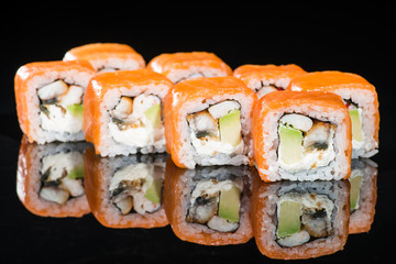 Tasty fresh sushi rolls with rice, cream cheese, shrimps, avocado, salmon and tobiko on dark background