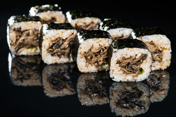 Japanese cuisine. Appetizing maki sushi rolls with rice, mushrooms, sauce and onion on dark background