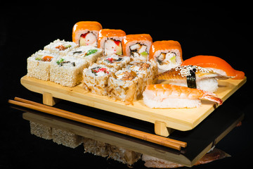 Set of different delicious sushi rolls on wooden board
