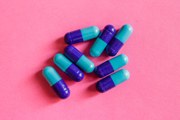 A pile of blue-purple capsules on pink background