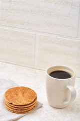 Close-up white cup of coffee with delicious waffles on white background, top view, vertical