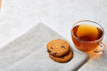Top view close up picture of tea in transparent cup with chocolate chips cookies on a cotton napkin on white background