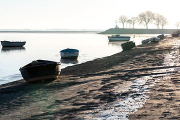 boats on the shore of a lake in the morning light