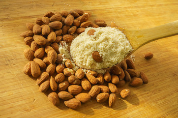 Almond flour in a wooden spoon on a background of nuts almonds.
