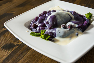 Dumplings with blueberries and cream. on a wooden background