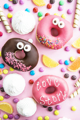 Junk food. Donuts, marmalade, chocolate sticks and balls, and meringues are scattered on a pink background. Unhealthy food concept. Top view, flat lay