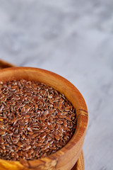 Flax seeds in bowl and flaxseed oil in glass bottle on light textured background, top view, close-up, selective focus
