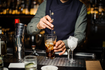Barman making an alcoholic cocktail in a glass