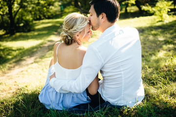 evening walk of a couple in love. A guy and a girl are sitting on the grass at sunset