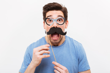 Shocked man in fake mustache and eyeglasses looking at camera