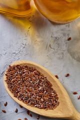 Wooden spoon with flax seeds on light textured background, top view, close-up, shallow depth of field, selective focus