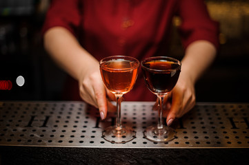Female baran holding two elegant glasses with cocktails
