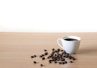 Coffee cup with coffee beans placed on a wooden table.