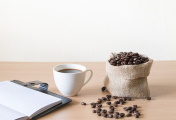 Coffee cup with coffee beans placed on a wooden table.