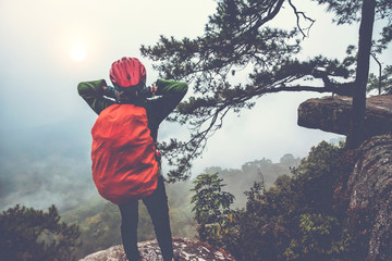 Asian women travel nature. Travel relax. Stand up landscapes on the cliff.  At sunrise which has fog guard. Thailand