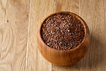 Flax seeds in wooden bowl on rustic wooden background, top view, shallow depth of field