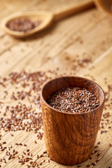 Flax seeds in wooden bowl on rustic wooden background, top view, shallow depth of field