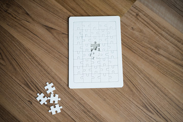 Fototapeta na wymiar Jigsaw white puzzle on wooden floor. Top view