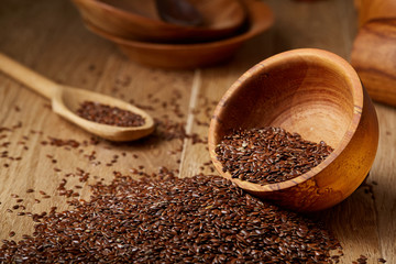 An overturned wooden bowl with linseeds on a rustic background, close-up, shallow depth of field, selective focus