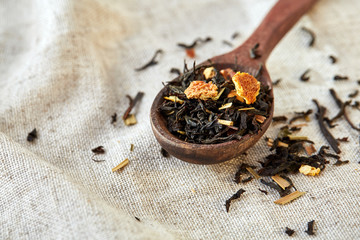 Closeup of a wooden spoon filled with scattered tea leaves, shallow depth of field, top view