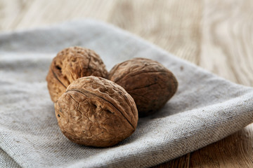 A stack of hard shells of walnuts piled together on light grey fabric cotton tablecloth, selective focus