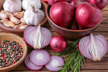 Bowls with red onion, garlic and spices on table