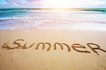Word Summer written on sand at ocean beach summer time