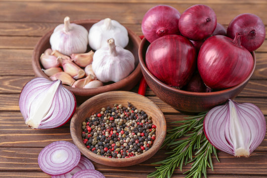 Bowls with red onion, garlic and spices on table
