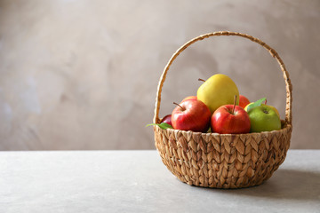 Ripe apples in wicker basket on table