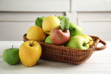 Juicy apples in basket on wooden table