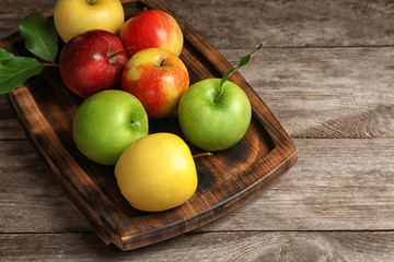 Tray with ripe juicy apples on wooden table