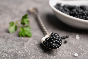 Fototapeta na wymiar Spoon with delicious black caviar on grey background