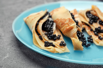 Thin pancakes with delicious black caviar on plate