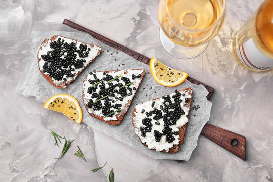 Sandwiches with delicious black caviar on wooden board