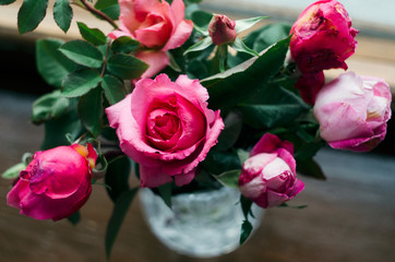 Homemade roses. Bouquet in a crystal vase on a wooden window. The concept of quiet and cozy village life, gardening and environmental friendliness