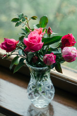 Homemade roses. Bouquet in a crystal vase on a wooden window. The concept of quiet and cozy village life, gardening and environmental friendliness