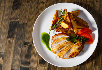 Grilled chicken breast with potato in a plate on wooden table