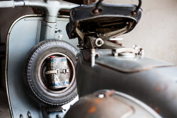 Spare wheel with oil can of old, rusty italian  scooter