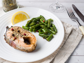 Healthy food. Baked red fish, pink salmon, salmon and green beans with a slice of lemon on a plate.